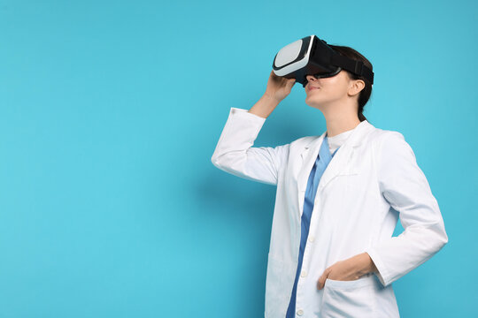 Modern technology. Doctor using virtual reality headset on light blue background. Space for text