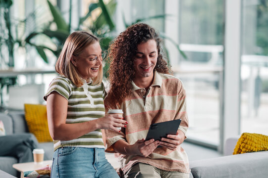 Young people collaborating on tablet in modern office - Powered by Adobe
