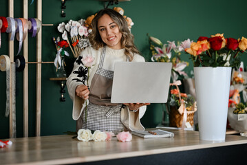 Florist woman holding laptop managing online flower shop