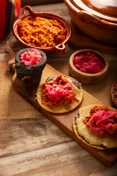 Panuchos, a typical dish from Yucatan, Mexico. A handmade, fried corn tortilla filled with beans, topped with cochinita pibil, pickled red onion, and habanero pepper.