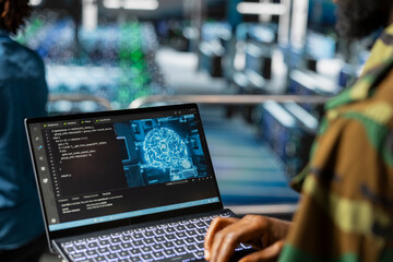 Black army technology specialist troubleshooting military pc systems in data center, networks using laptop. Soldier in command center server room using notebook.