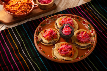 Panuchos, a typical dish from Yucatan, Mexico. A handmade, fried corn tortilla filled with beans, topped with cochinita pibil, pickled red onion, and habanero pepper.
