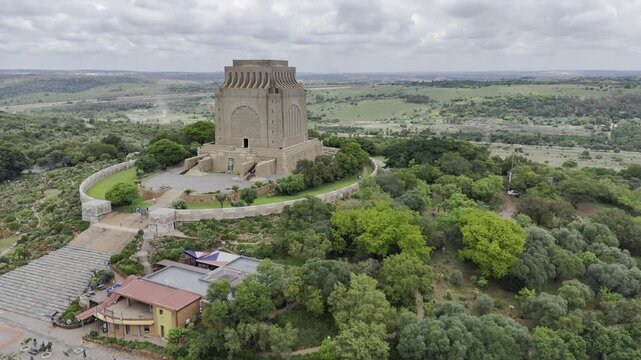 Drone flies forward at an angle toward the Voortrekker Monument  on a cloudy day in Pretoria, South Africa