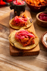 Panuchos, a typical dish from Yucatan, Mexico. A handmade, fried corn tortilla filled with beans, topped with cochinita pibil, pickled red onion, and habanero pepper.