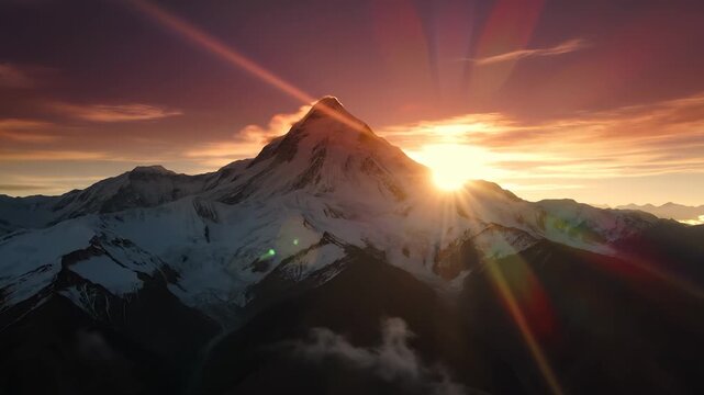 A magnificent mountain rises majestically as the sun breaks the horizon, illuminating the snowy peaks with a warm glow. The surrounding landscape features enchanting valleys and ru