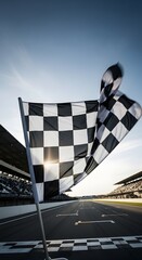 Checkered flag waving at the finish line of a race track with grandstands and a clear sky.