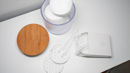 Cotton rounds and swabs arranged with a ribbed plastic dispenser and a natural wooden lid on a...