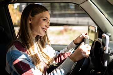 Woman smiling, driving car enjoying road trip