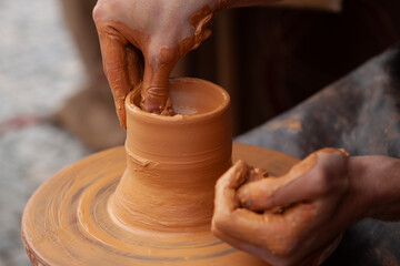 Potter a moldar argila  numa roda de cerâmica, criando um pequeno copo em cerâmica numa oficina...