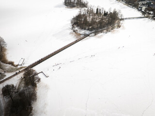 Aerial view of a serene, snow-covered landscape featuring a bridge connecting to an island, a winter scene evoking tranquility, Trakai, Trakai, Lithuania.