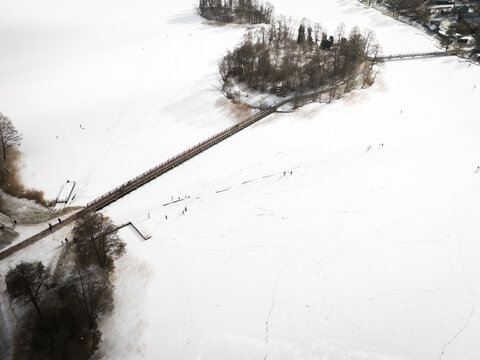 Aerial view of a serene, snow-covered landscape featuring a bridge connecting to an island, a winter scene evoking tranquility, Trakai, Trakai, Lithuania.