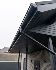 Fototapeta premium Black gutter system with downspout on modern brick house terrace roof