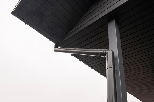 Low angle view of black rain gutter system on wooden roof soffit
