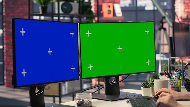 Professional woman works at modern workspace using green screen on dual monitors setup. High tech office environment enhances productivity, IT professionals and content creation. Camera B.