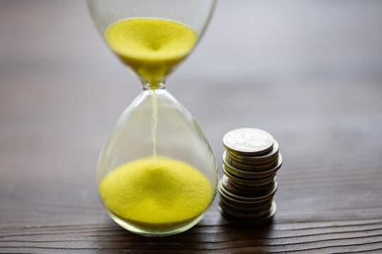 Close-Up of a Yellow Hourglass with Coins - Powered by Adobe