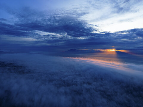 Aerial view of the sun's golden rays piercing through a sea of clouds, painting the sky with vibrant hues, Klaten Regency, Central Java, Indonesia.