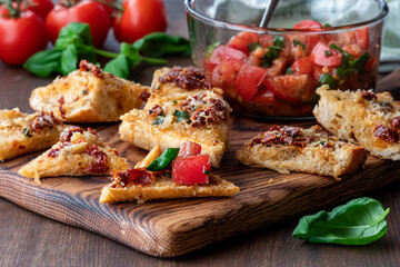 Pieces of toasted bread with bruschetta topping in a bowl in behind.