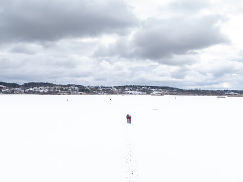 Aerial view of a seemingly endless expanse of pristine white snow stretching towards the horizon under a brooding sky, Moluvenai, Trakai district, Lithuania.