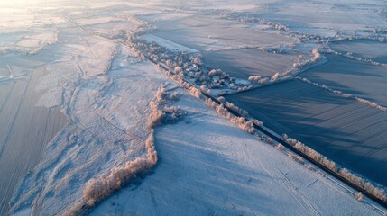 Winter landscape with snowy fields and rural roads at sunrise near a small village