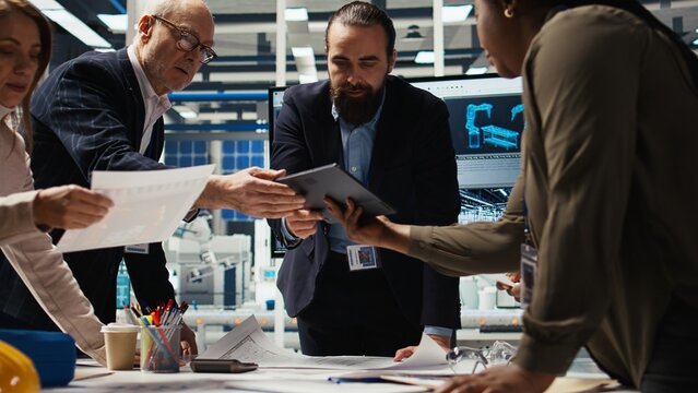 Industrial plant managers and investors analyze technical production data on paperwork documents. Factory management checking manufacturing automation advancements documentation, camera A