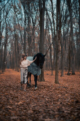 Fototapeta premium Walking with a horse through a forest path during autumn in the late afternoon