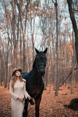 Obraz premium Woman stands with a horse in a forest during autumn while touching its face gently