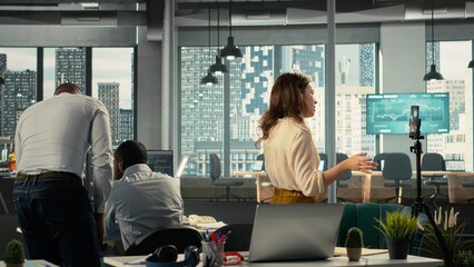Corporate staff filming a video advertisement for a commercial in office, collaborating on data visualization and report sharing. Work team discusses resource allocation and targets.