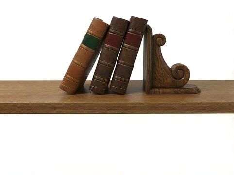 Three antique books leaning on a wooden shelf, supported by a decorative bookend.