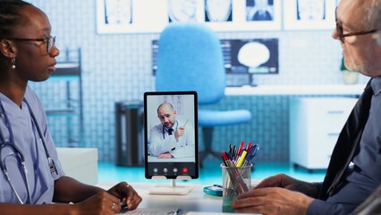 Nurse discussing with patients while on videocall with an expert, receiving professional diagnosis and different advice for recovery. Doctor supporting clients via internet conference. Camera B.