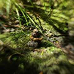 A small statue of a person is sitting on a pile of rocks in a grassy area