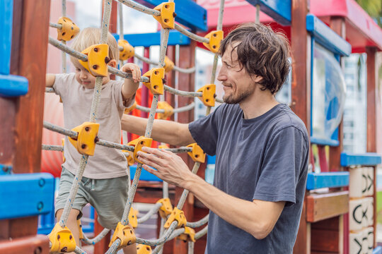 A man playing with his small son on a playground, laughing and engaging in active fun together in a bright outdoor setting. Family bonding, early childhood development and healthy outdoor lifestyle