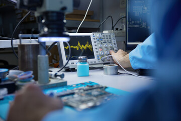 A technician is diligently working on a circuit board while utilizing a microscope for precision © Nomad_Soul