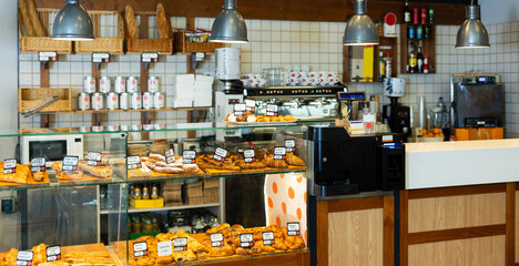Interior of traditional Spanish bakery shop with racks and showcase full of fresh baguettes, rustic loaves, and delicious pastries
