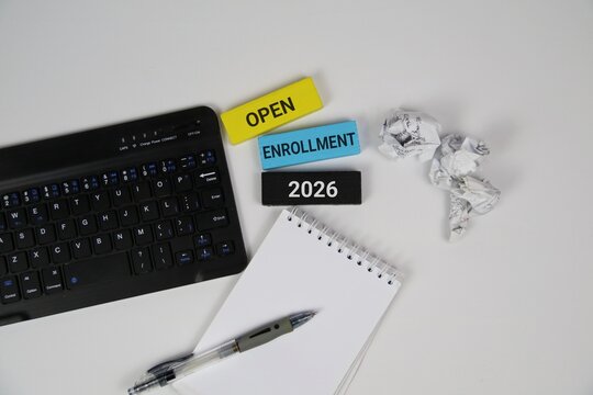 White background featuring a laptop keyboard, spiral notebook, and pen, with colorful blocks showing Open Enrollment 2026. Great for education, courses, and business enrollment themes.