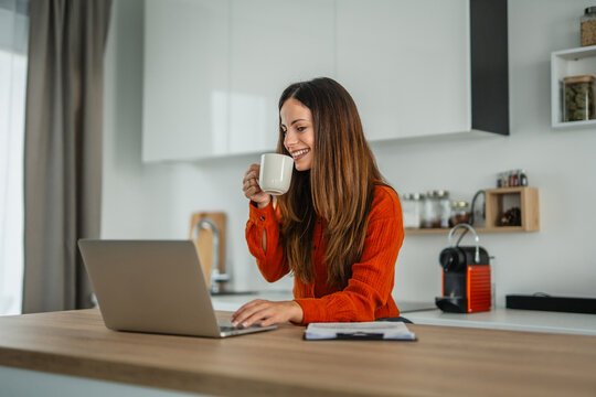 Young woman drinking coffee working online from home - Powered by Adobe
