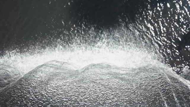 Water flows over a rocky edge, splashing and creating ripples, highlighting the dynamism of nature's beauty. Concept water, nature, movement, landscape.