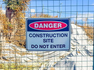 Photograph of a Danger Warning Sign on a fence barricade notifying people not to enter a small construction site in regional New South Wales, Australia. 