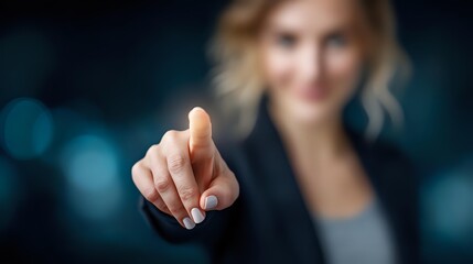 Businesswoman pointing finger at virtual screen, making digital selection against blurred blue background. Professional technology concept.