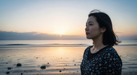 Young woman gazes thoughtfully toward the horizon during a tranquil seaside sunset