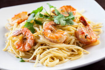 Spaghetti with shrimp and white sauce on a white plate. 