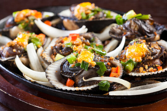 Vietnamese steamed clams with fresh grilled ingredients on a cast-iron pan.