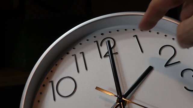Daylight Saving Time. The clock hands move from 2:00 to 3:00. Close-up of the hands, with a man's hand.