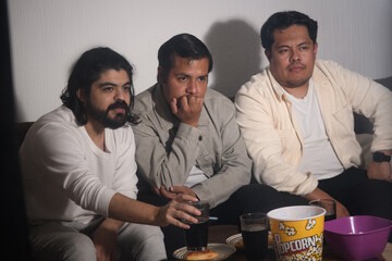 Three friends showing concern while watching a dramatic scene
