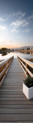 Fototapeta premium Wooden boardwalk leading to a calm lake at sunrise with clear skies.