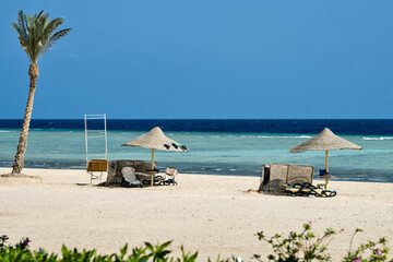 Relaxing beach view at an Egyptian resort with sun umbrellas, loungers, and a calm sea beyond.