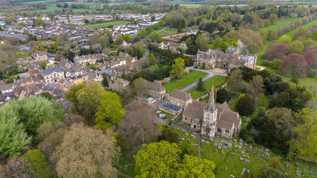 Aerial view of the ancient church spire piercing the sky amidst Corsham Court's lush greenery and historic buildings, Corsham Court, Wiltshire, United Kingdom.