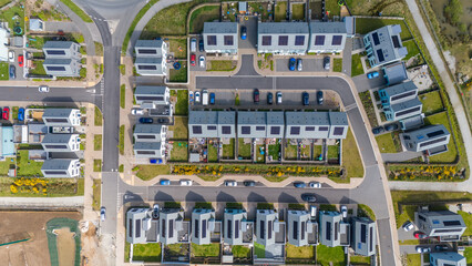 Aerial view of rows of modern homes with solar panels glinting under the sun, neatly arranged in a newly developed estate, Saint Austell, United Kingdom.