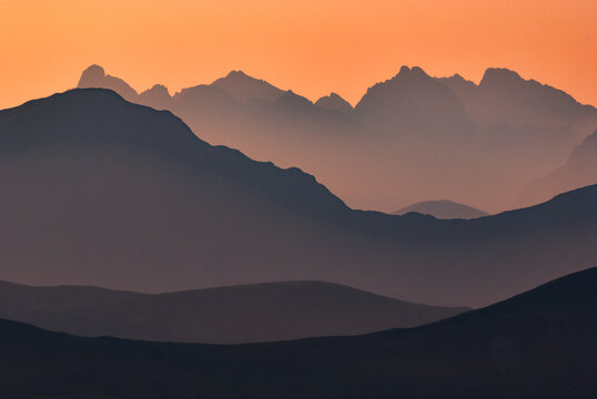 Aerial view of the majestic Western Tatras mountains silhouetted against a fiery sunset, where peaks fade into the horizon, Jamnik, Zilina Region, Slovakia.