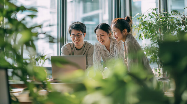 Three office workers happily gathered around a laptop screen. Perfect for business, teamwork, technology, and corporate communication concepts.