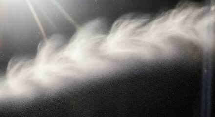Bright light illuminates a swirling stream of fine mist or particles against a dark background with visible specks